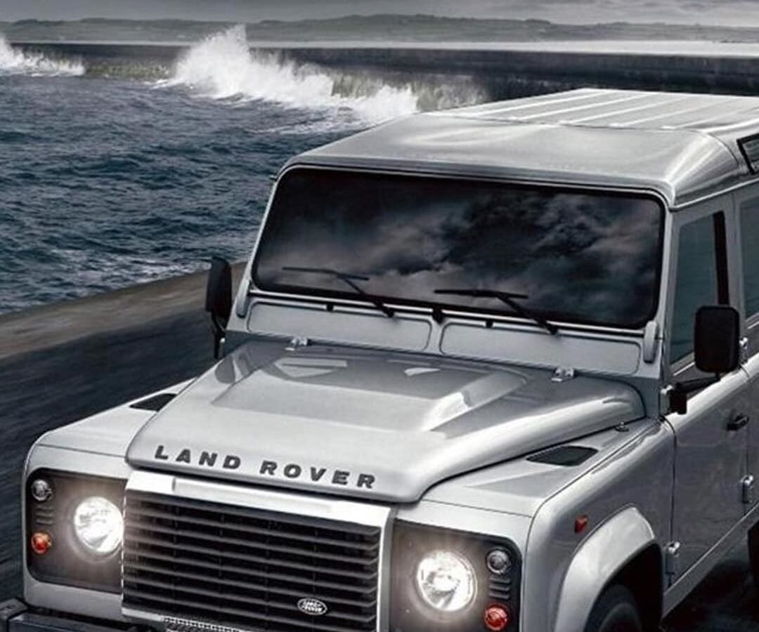 Land Rover Defender driving along a rocky coastline