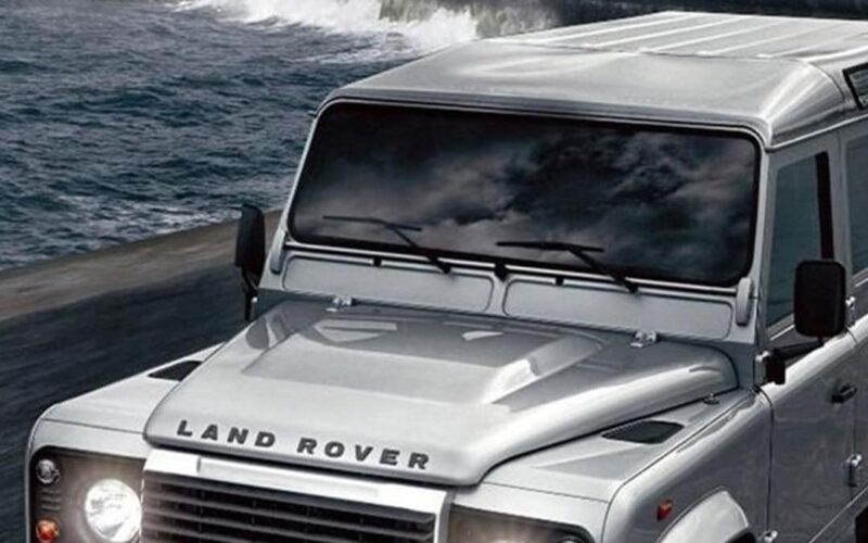 Land Rover Defender driving along a rocky coastline